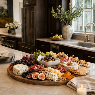 A beautifully layered charcuterie moment featuring artisanal cheeses, fresh fruit, warm wood tones, and organic ceramic serving pieces designed for effortless entertaining.
