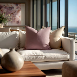 20x20 mauve linen throw pillow layered with neutral beige pillows on an ivory linen sofa in a luxury Newport Beach modern contemporary living room with ocean view windows and soft natural light