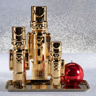 Medium gold ceramic soldier figurine with high-gloss metallic finish displayed beside large gold soldier on festive coffee table – modern sculptural holiday décor accent reflecting warm light in elegant neutral living room setting.