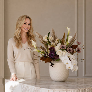 Mel Deakins, owner of Third & Main standing in front of a luxe marble counter with a vase filled with fall florals
