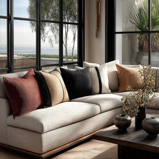 Neutral sofa styled with maroon so soft linen pillow layered with camel, black, and cream pillows in a modern coastal living room.