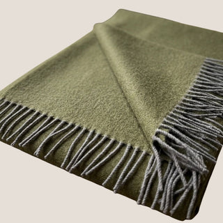 Close-up of the olive green baby alpaca throw showing its soft brushed texture, woven surface, and contrasting gray fringe.