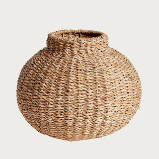 Round handwoven seagrass vase with sculptural shape and natural woven texture, styled as a decorative accent
