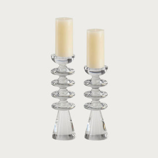 Set of two clear crystal pillar candle holders measuring 13.7 and 12 inches high with stacked disc details, tapered bases, and ivory pillar candles.