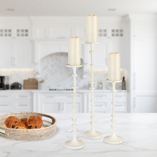 Set of three tall white aluminum pillar candle holders with a sculptural design, displayed with pillar candles (not included); ideal for modern or transitional or modern farmhouse home décor. Fall decor, Winter Decor, Holiday decor