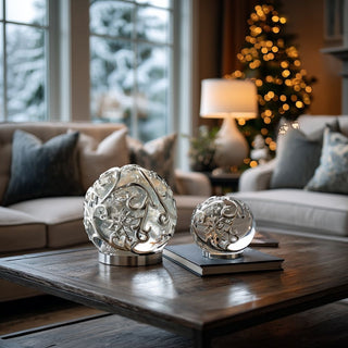 Set of two silver scrolled snowflake LED water spinning globes displayed on wooden coffee table in cozy living room with holiday décor and Christmas tree lights – elegant illuminated decorative spheres with swirling glitter and built-in timer for refined winter styling.
