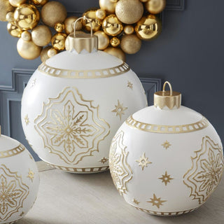 Set of white and gold resin ornaments in three sizes with metallic detailing displayed near gold wreath – luxurious handcrafted holiday décor for mantels, consoles, or entryway styling.