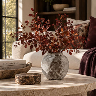 Short Tuscan Ceramic Vase with a rounded silhouette and mottled gray-brown stone-look finish, styled with burgundy and rust autumn branches on a travertine coffee table in a warm modern living room.