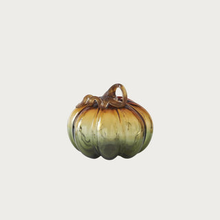 Small ombre green and amber glass pumpkin measuring 4.5 inches high by 5 inches wide with transparent ribbed glass and curled brown stem.