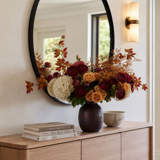 Small dark brown mango wood vase styled with cream hydrangeas, burgundy flowers, camel roses, and autumn foliage on a wood console.