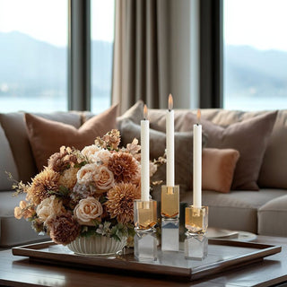 Small Vienna Artistry smoke and gold crystal candle holder styled with taller matching holders and ivory taper candles on coffee table with floral arrangement.
