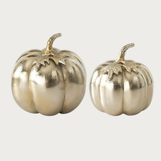 Medium and large soft matte gold aluminum pumpkins shown together for size comparison, each with rounded ribs, sculpted leaves, and curved stems.
