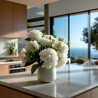 Six stem white real touch hydrangea floral arrangement in a white ceramic vase styled on a marble kitchen island in a luxury Malibu California modern contemporary home with ocean views and abundant natural light.