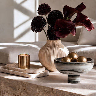 9.75 Inch Black and White Swirled marble bowl styled with matte gold orbs on a stone coffee table in a modern living room 