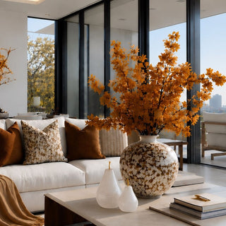 Set of two frosted white glass pears with gold stems styled on a coffee table in a neutral living room with brown, cream, and gold decor.