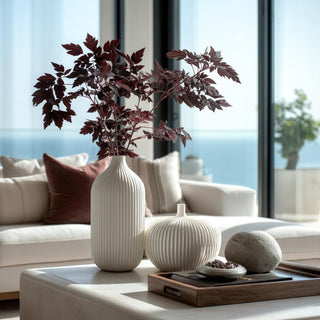 Tall ivory ribbed vase with faux dry burgundy cimicifuga stems – artificial fall foliage for coffee table styling in modern neutral living room.