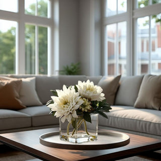 White real touch dahlia arrangement  by Third & Main in a square glass vase on a round tray atop a modern wood coffee table in a neutral living room with large windows