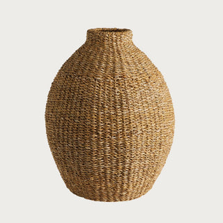 Teardrop shaped woven seagrass vase with natural texture and sculptural silhouette, styled as a warm organic floor accent