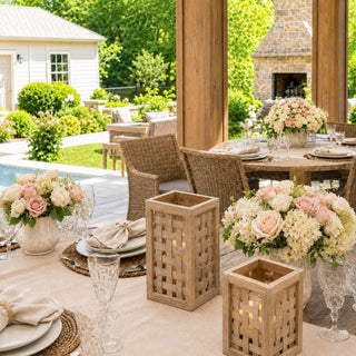 A warm outdoor entertaining moment featuring woven teak lanterns, soft blush florals, layered textures, and abundant natural light designed for relaxed luxury living.
