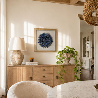 16 inch Gold Framed Blue lapis flower wall art in a gold frame displayed above a natural oak sideboard, styled with a ceramic lamp, trailing greenery, and warm sunlight in a neutral luxury interior.