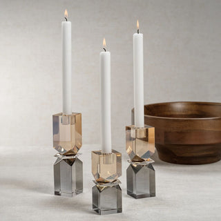 Three crystal candle holders with lit candles on a neutral background
