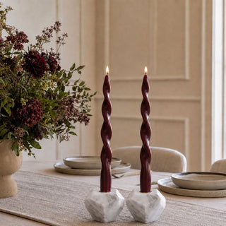 Pair of 4 Inch Trinity White Marble Taper Candle Holders styled on a dining table with burgundy taper candles, a neutral runner, and a moody floral arrangement.