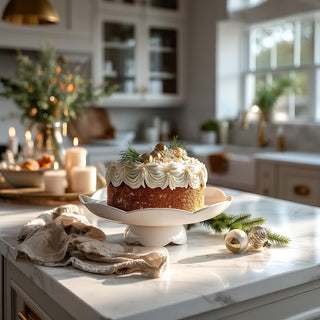 A white pedestal cake stand styled on a kitchen island with candles and greenery—an easy way to elevate desserts and everyday entertaining.