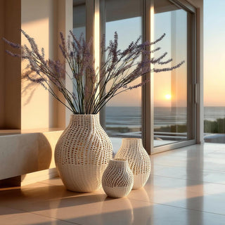 White ceramic latticework vase trio in graduated sizes styled with light purple blossom branch stems in a Santa Monica entryway at golden hour