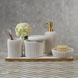 white ribbed bathroom accessory set with soap dispenser toothbrush holder canister and soap dish styled on marble tray with gold accents and neutral decor
