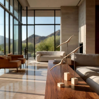 Set of three modern wood and iron bird sculptures styled on a walnut console table in a luxury Scottsdale Arizona contemporary living room with floor-to-ceiling windows and desert mountain views.