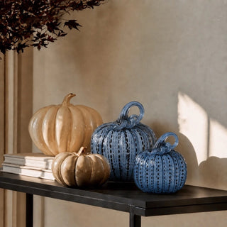 Blue speckled handblown glass pumpkins styled with warm neutral glass pumpkins on a black console in natural light for modern fall decor.