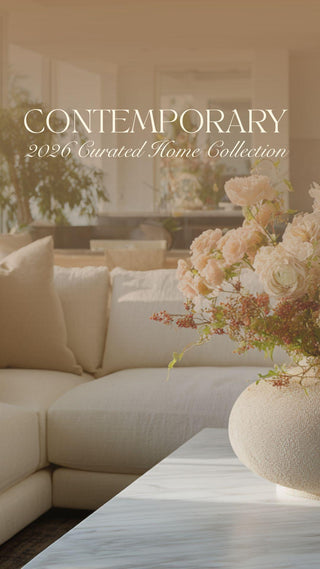 Bright contemporary living room featuring a neutral sectional sofa layered with textured beige pillows, a sculptural stone vase filled with soft blush and ivory florals, and a minimalist modern interior with natural light and ocean views