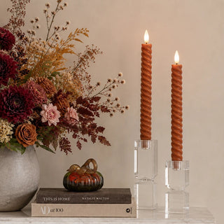 Set of two rust-colored twist LED taper candles with sculptural wax spirals and flameless light for tabletop and fall home decor.