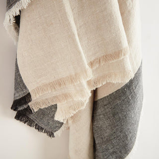 European linen throw blanket in flax and charcoal, draped over furniture