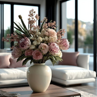 Flocked purple king protea stem styled in a soft blush and cream spring floral arrangement on a modern living room coffee table.