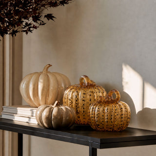 Golden amber speckled handblown glass pumpkins styled with neutral glass pumpkins on a black console in warm natural light for fall decor.
