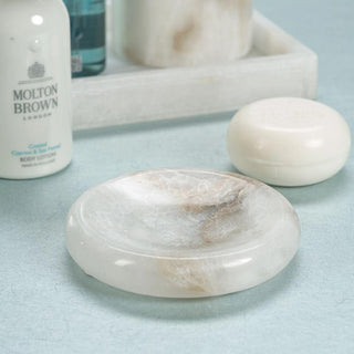 Round alabaster soap dish styled on a bathroom vanity with a bar of soap
